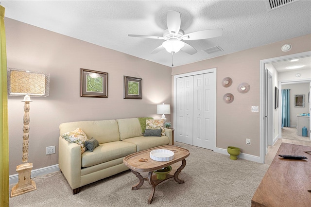 carpeted living room with a textured ceiling and ceiling fan