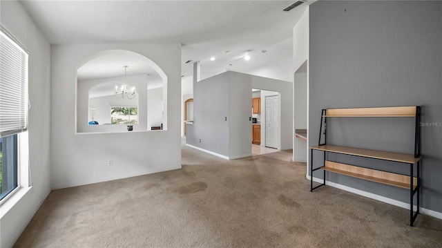 carpeted empty room with vaulted ceiling and a notable chandelier