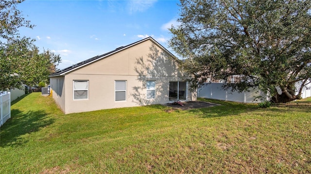 rear view of property with central AC unit and a lawn