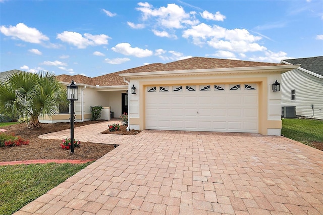 view of front of home with a garage and central air condition unit