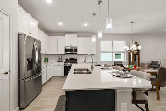 kitchen featuring appliances with stainless steel finishes, white cabinetry, pendant lighting, and an island with sink