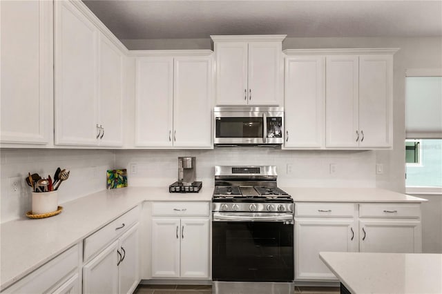 kitchen with backsplash, appliances with stainless steel finishes, and white cabinetry