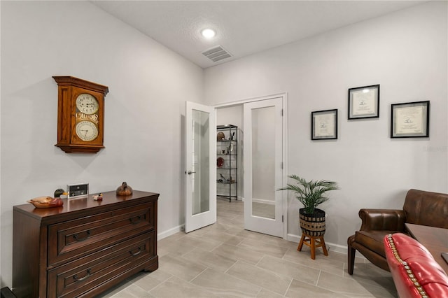 living area featuring french doors and light tile patterned floors