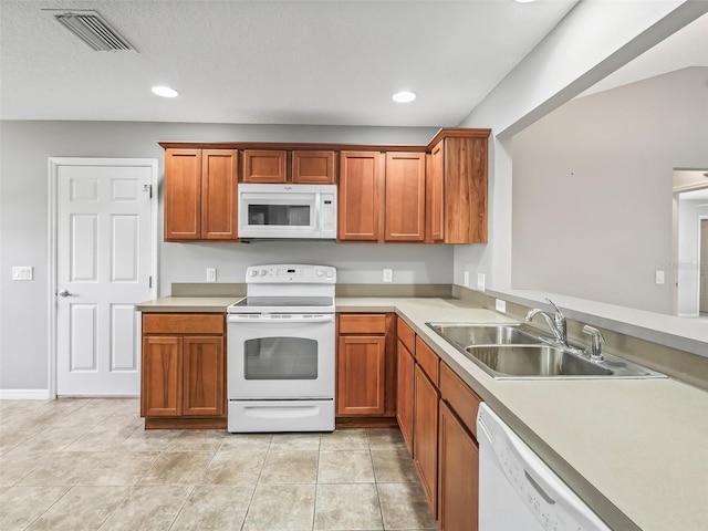 kitchen featuring a textured ceiling, sink, light tile patterned floors, and white appliances