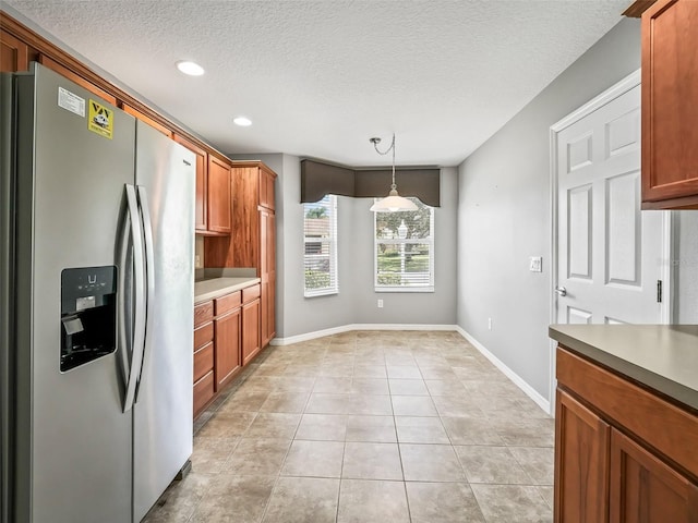 kitchen with stainless steel fridge, a textured ceiling, hanging light fixtures, and light tile patterned floors