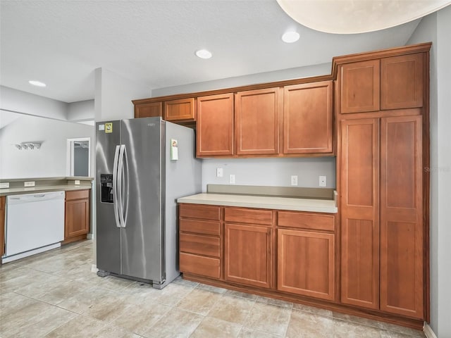 kitchen with stainless steel fridge, dishwasher, and a textured ceiling