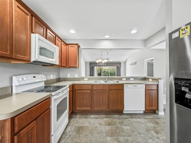 kitchen featuring lofted ceiling, kitchen peninsula, pendant lighting, sink, and white appliances