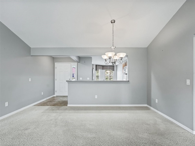 carpeted spare room featuring vaulted ceiling and an inviting chandelier