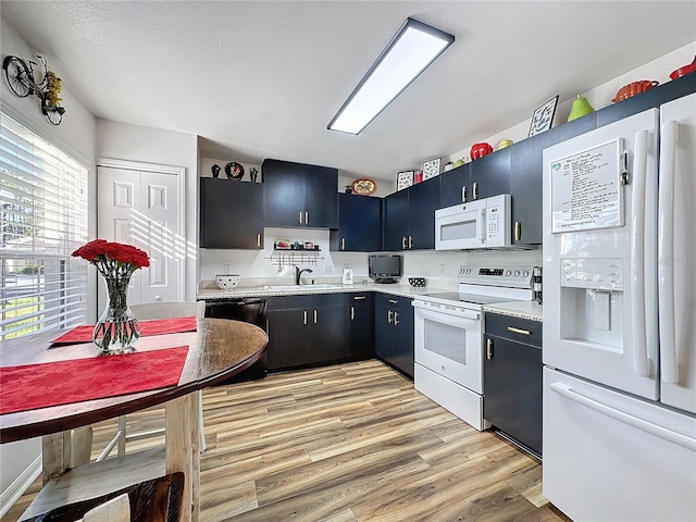 kitchen with sink, light hardwood / wood-style floors, and white appliances