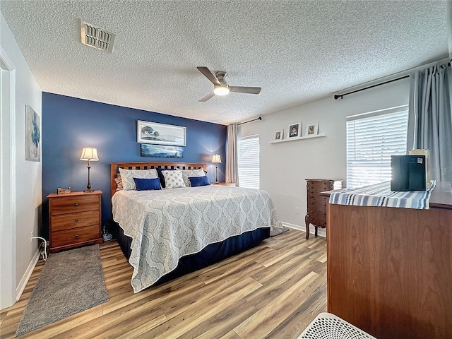 bedroom featuring light hardwood / wood-style floors, a textured ceiling, and ceiling fan