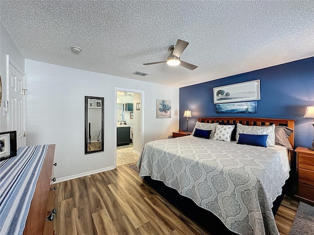 bedroom featuring dark hardwood / wood-style floors, ensuite bath, a textured ceiling, and ceiling fan