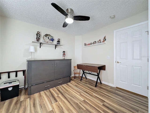 interior space featuring ceiling fan, wood-type flooring, and a textured ceiling