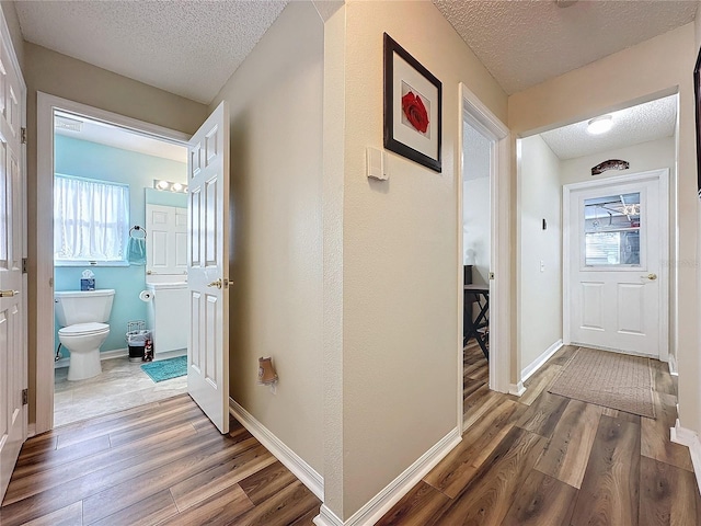 corridor with a textured ceiling and hardwood / wood-style flooring