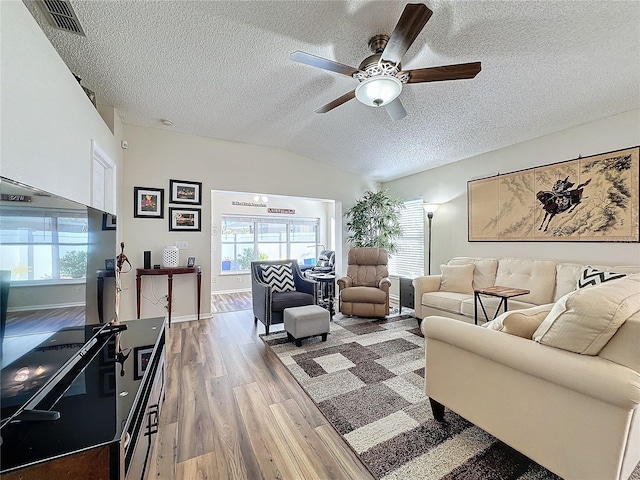 living room featuring hardwood / wood-style floors, ceiling fan, a textured ceiling, and vaulted ceiling