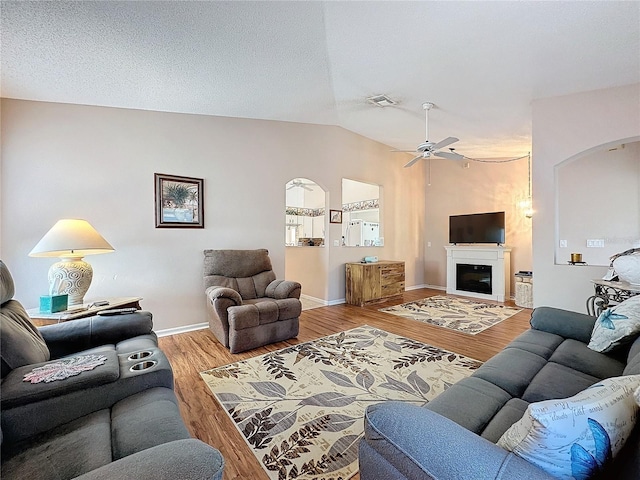 living room with ceiling fan, wood-type flooring, and vaulted ceiling