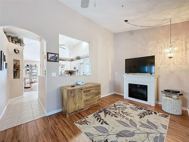 living room featuring vaulted ceiling, light hardwood / wood-style flooring, a textured ceiling, and a chandelier