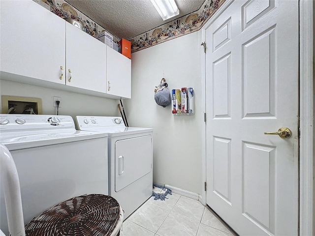 laundry room featuring light tile patterned floors, a textured ceiling, cabinets, and washing machine and clothes dryer