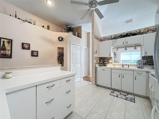 kitchen with backsplash, white dishwasher, light tile patterned flooring, white cabinetry, and a textured ceiling