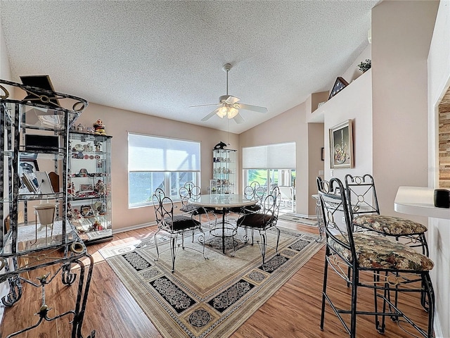 dining area featuring light hardwood / wood-style flooring, a textured ceiling, ceiling fan, and vaulted ceiling