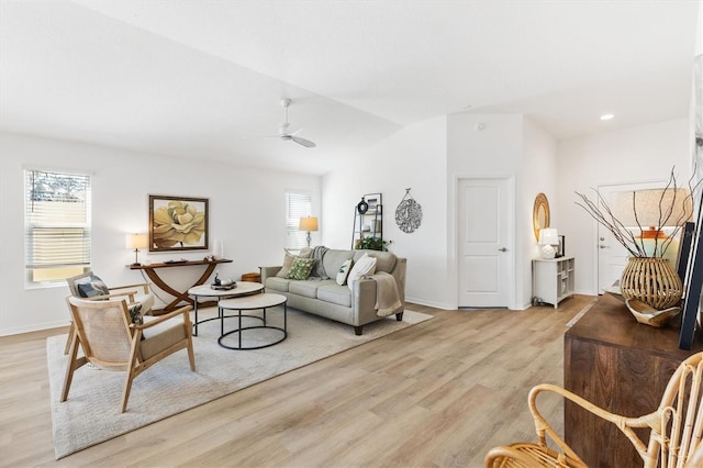 living room with ceiling fan, vaulted ceiling, and light wood-type flooring