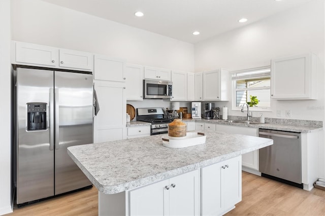 kitchen with white cabinetry, light hardwood / wood-style floors, appliances with stainless steel finishes, and a kitchen island