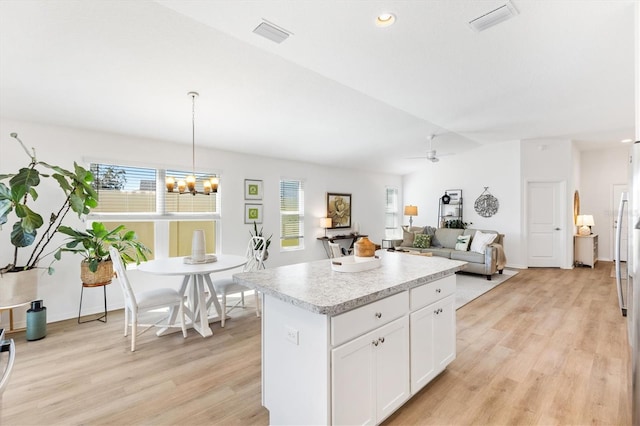 kitchen with white cabinetry, decorative light fixtures, ceiling fan with notable chandelier, and light wood-type flooring