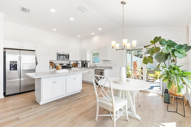 kitchen featuring white cabinetry, light hardwood / wood-style flooring, decorative light fixtures, and stainless steel appliances