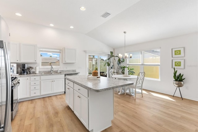 kitchen with white cabinets, a center island, hanging light fixtures, and plenty of natural light