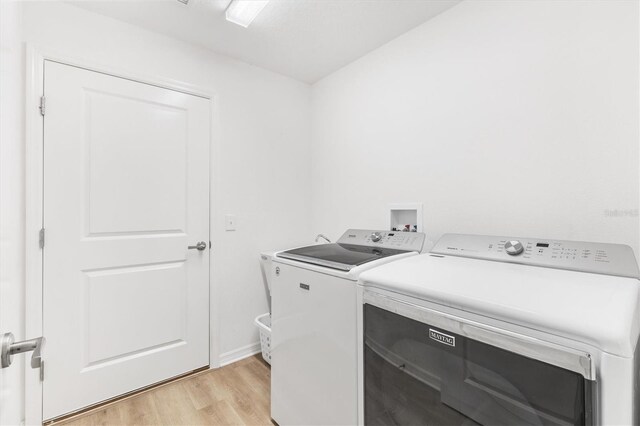 clothes washing area featuring light hardwood / wood-style flooring and washing machine and dryer