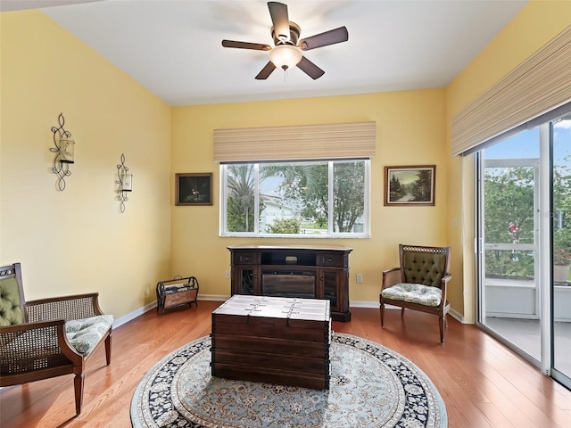 living area with a wealth of natural light, light hardwood / wood-style floors, and ceiling fan