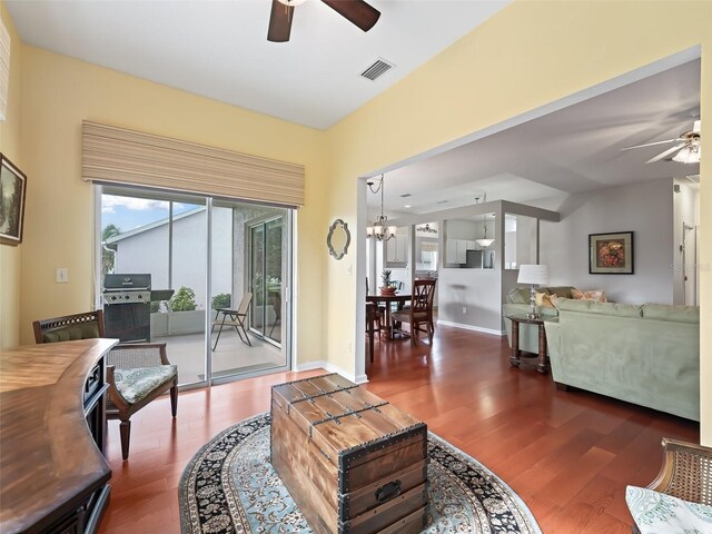 living room featuring dark wood-type flooring and ceiling fan with notable chandelier