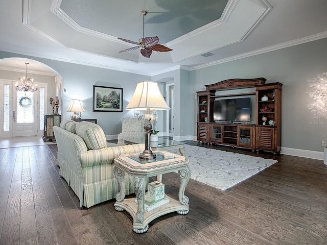 living room featuring ceiling fan, a tray ceiling, ornamental molding, and dark hardwood / wood-style flooring