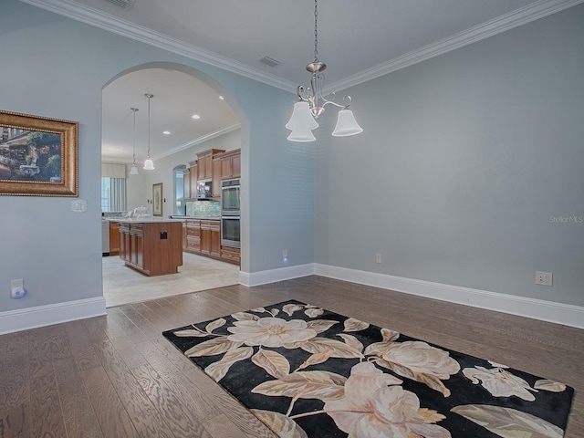 spare room with light hardwood / wood-style floors, ornamental molding, and an inviting chandelier