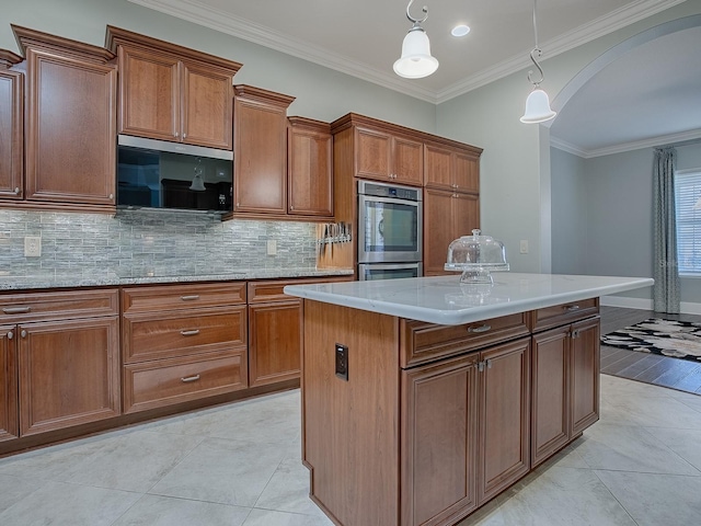 kitchen with a kitchen island, stainless steel appliances, pendant lighting, crown molding, and decorative backsplash