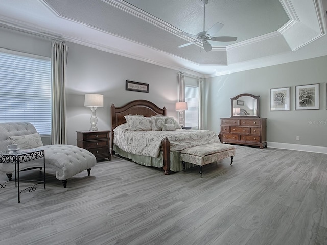 bedroom with light hardwood / wood-style flooring, a tray ceiling, crown molding, a textured ceiling, and ceiling fan