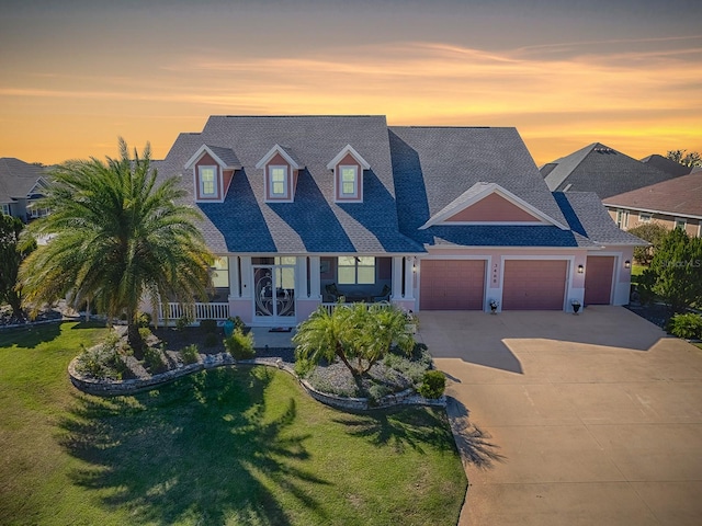 view of front of property with a yard, a porch, and a garage