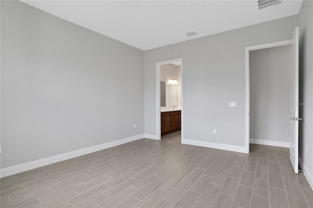 unfurnished bedroom featuring ensuite bathroom and light hardwood / wood-style flooring