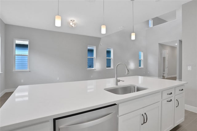 kitchen with a center island with sink, sink, hanging light fixtures, stainless steel dishwasher, and white cabinetry