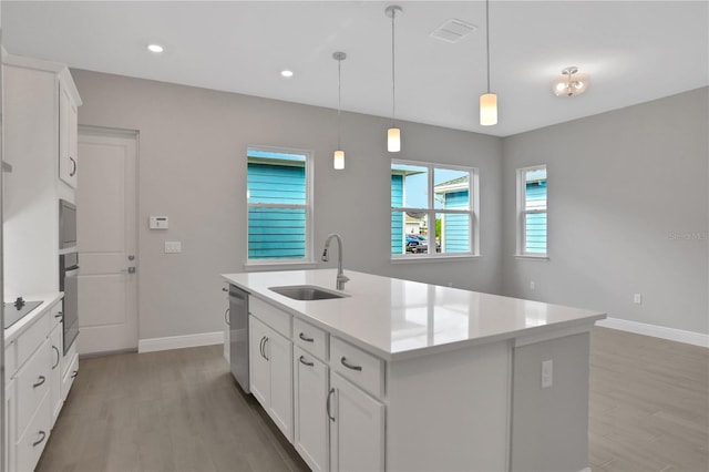 kitchen with light wood-type flooring, stainless steel appliances, sink, a center island with sink, and white cabinets