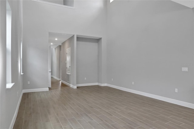 unfurnished living room featuring light hardwood / wood-style flooring and a towering ceiling