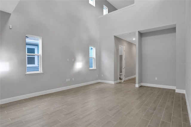 unfurnished living room featuring a high ceiling and light hardwood / wood-style flooring