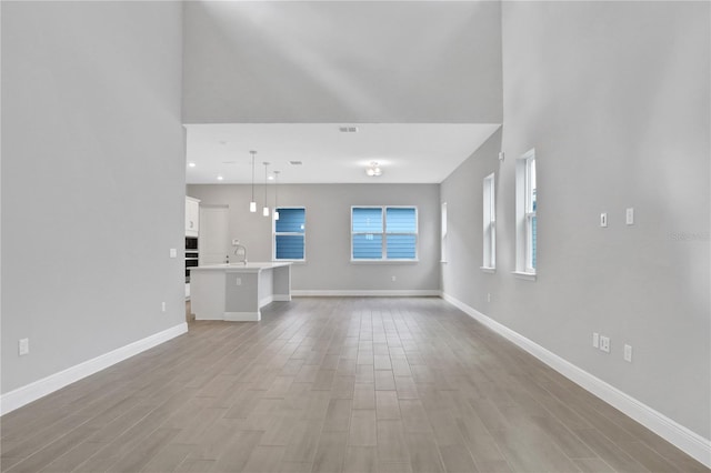 unfurnished living room with light hardwood / wood-style flooring and sink