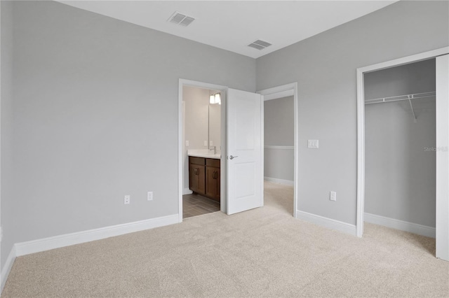 unfurnished bedroom with light colored carpet, connected bathroom, and a closet