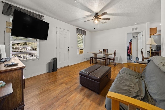 living room with ceiling fan, a textured ceiling, and hardwood / wood-style flooring