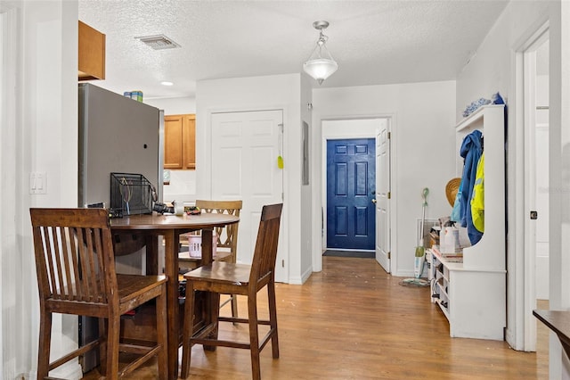 dining space featuring light hardwood / wood-style floors and a textured ceiling