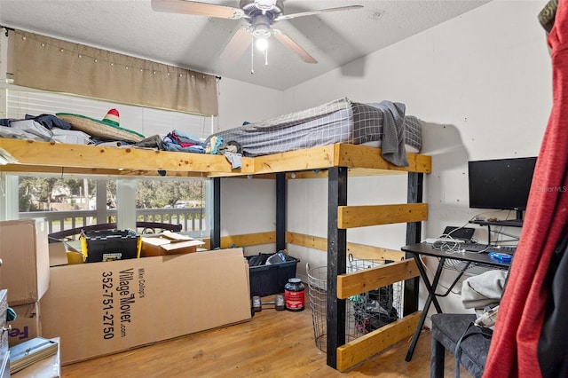 bedroom with ceiling fan, wood-type flooring, and a textured ceiling