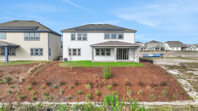 rear view of house featuring solar panels and central air condition unit