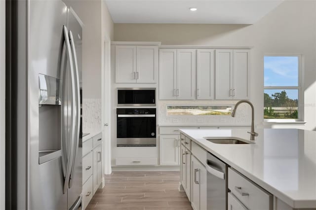 kitchen with white cabinetry, sink, stainless steel appliances, and decorative backsplash