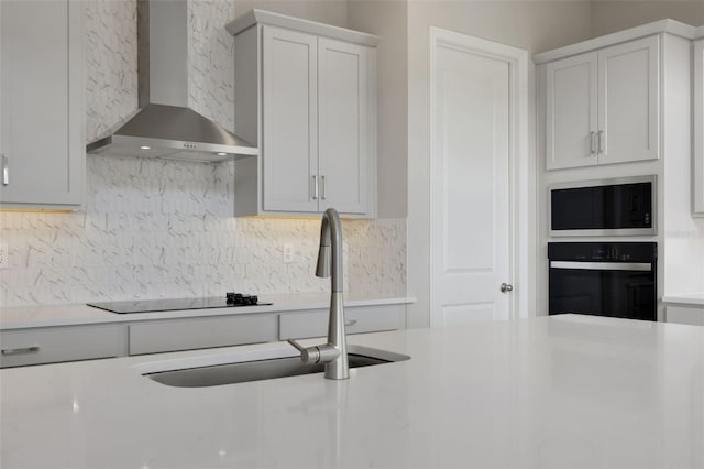 kitchen featuring wall chimney exhaust hood, white cabinets, black appliances, backsplash, and sink