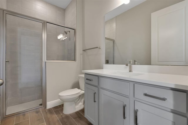 bathroom with toilet, vanity, and a shower with shower door